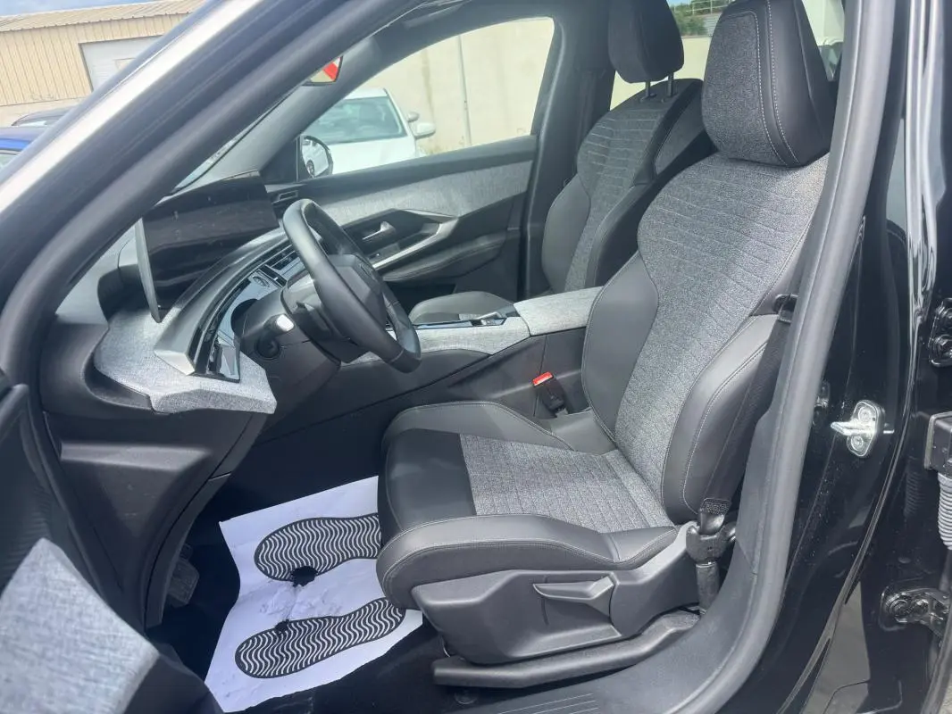 Vue intérieure côté conducteur du Peugeot 5008 noir 2025, sièges tissu et cuir avec tableau de bord moderne.