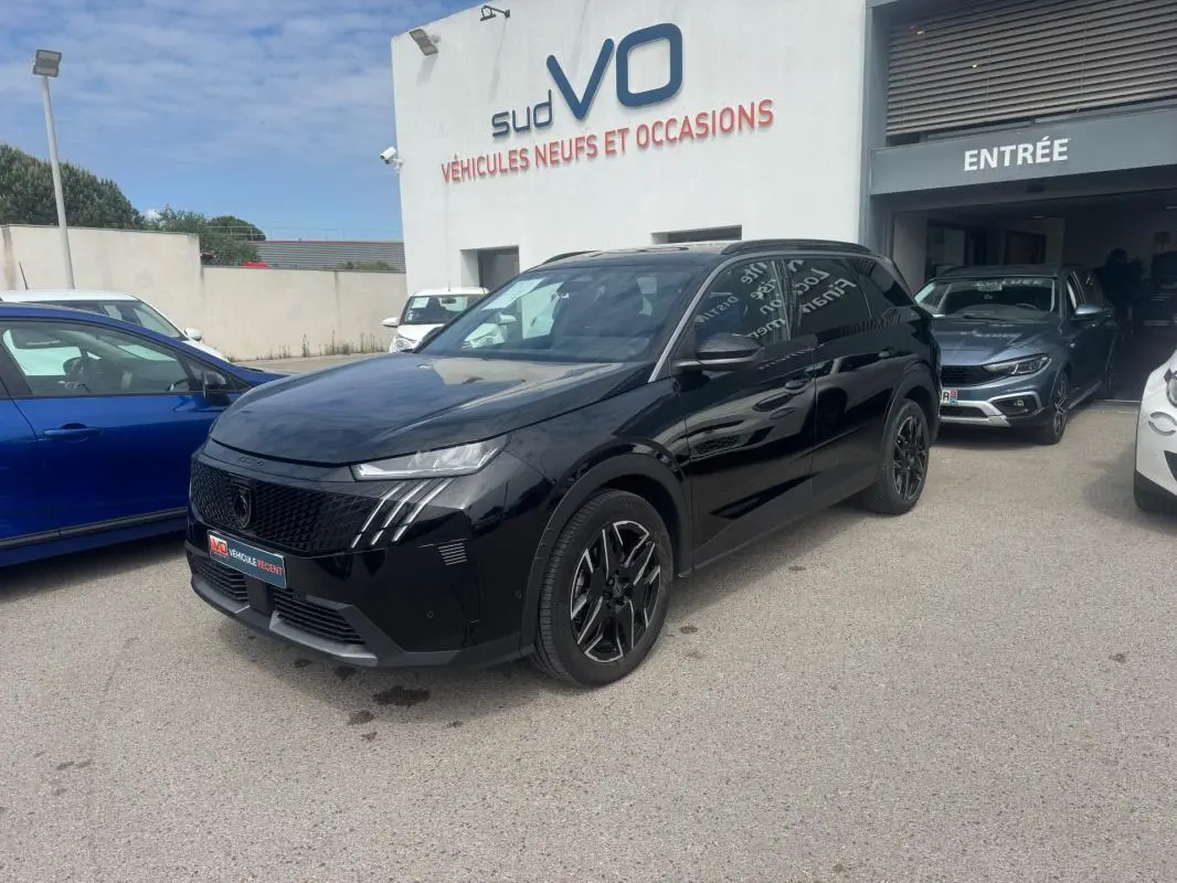 Peugeot 5008 Hybrid noir en 3/4 avant droit, avec jantes alliage noires et barres de toit visibles sur parking.