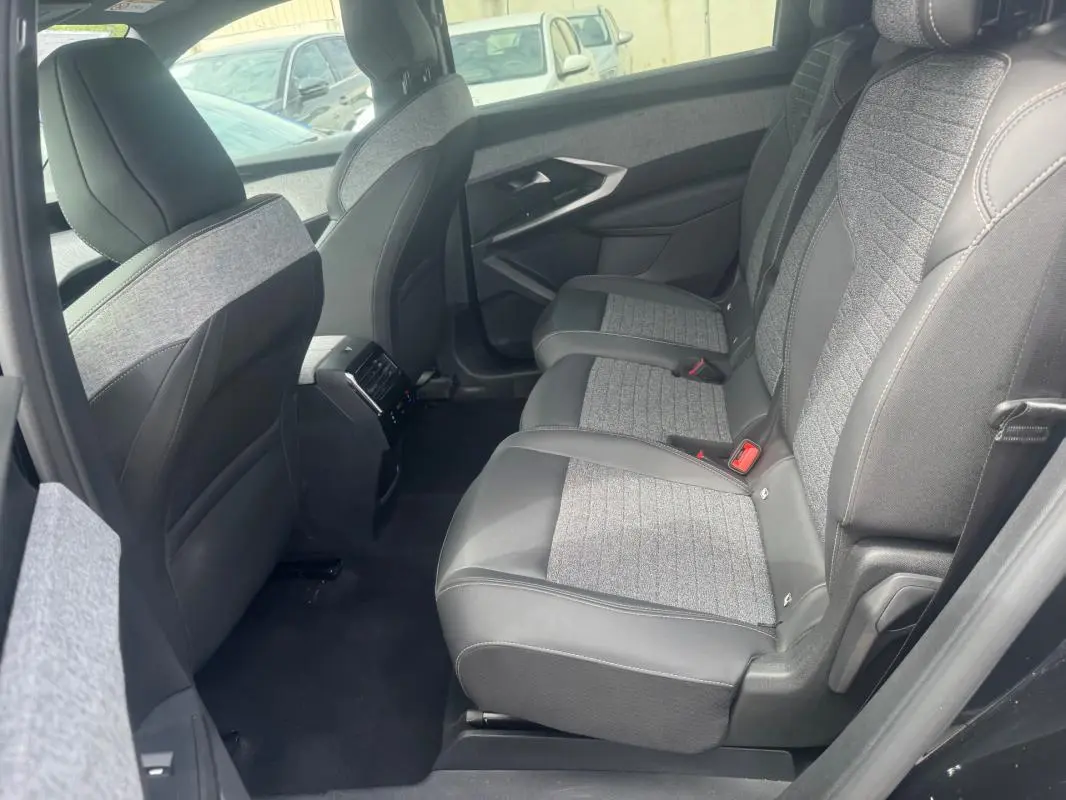 Vue latérale droite de l'intérieur arrière du Peugeot 5008 noir, sièges tissu et cuir avec console centrale et aérateurs.