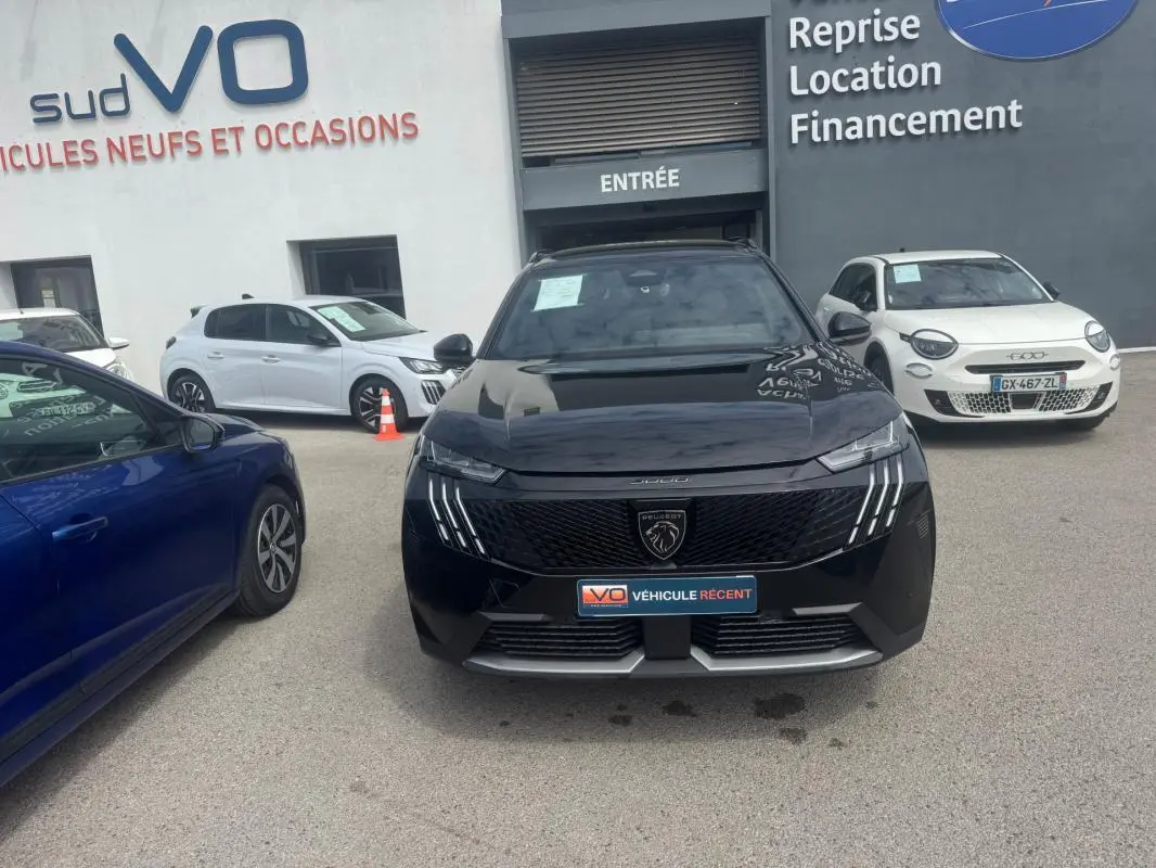 Peugeot 5008 Hybrid noir vue de face, avec calandre distinctive et feux à LED verticaux allumés.