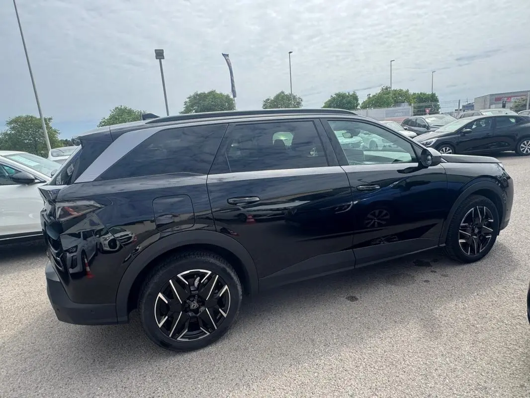 Peugeot 5008 Hybrid noir vue de profil côté gauche, avec jantes alliage 19 pouces et barres de toit visibles.