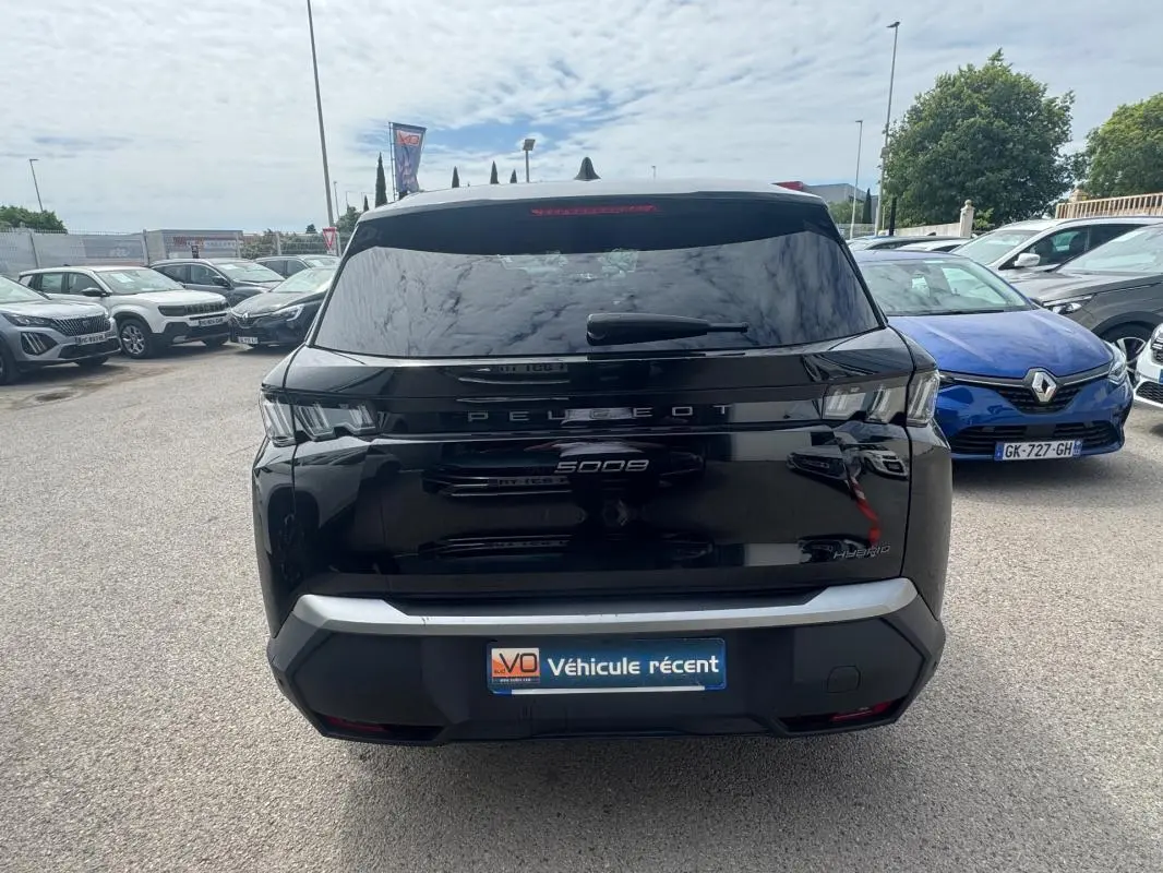 Vue arrière d’un Peugeot 5008 noir 2025 avec feux LED et badge Hybrid, stationné en extérieur.