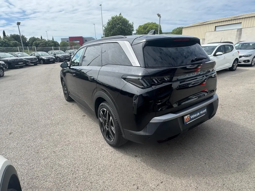 Peugeot 5008 Hybrid noir vue 3/4 arrière droit avec jantes alliage 19 pouces et barres de toit visibles.