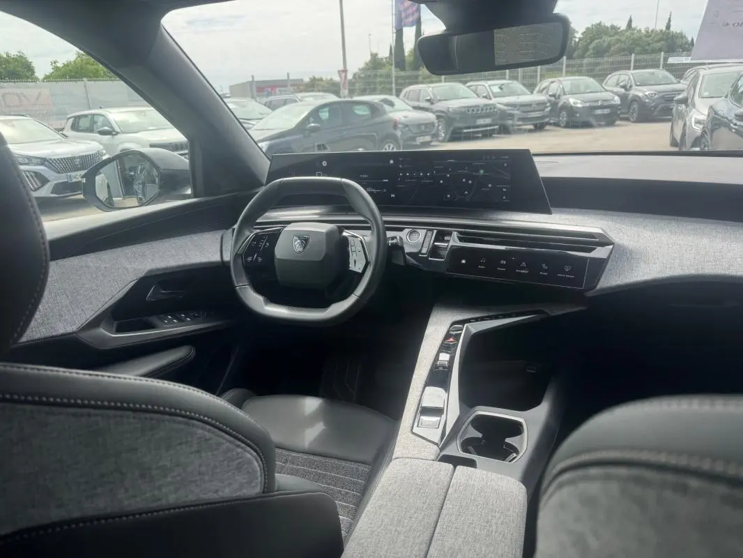 Vue intérieure du Peugeot 5008 Hybrid 145 ch Allure 2025, montrant le cockpit numérique et le volant compact.