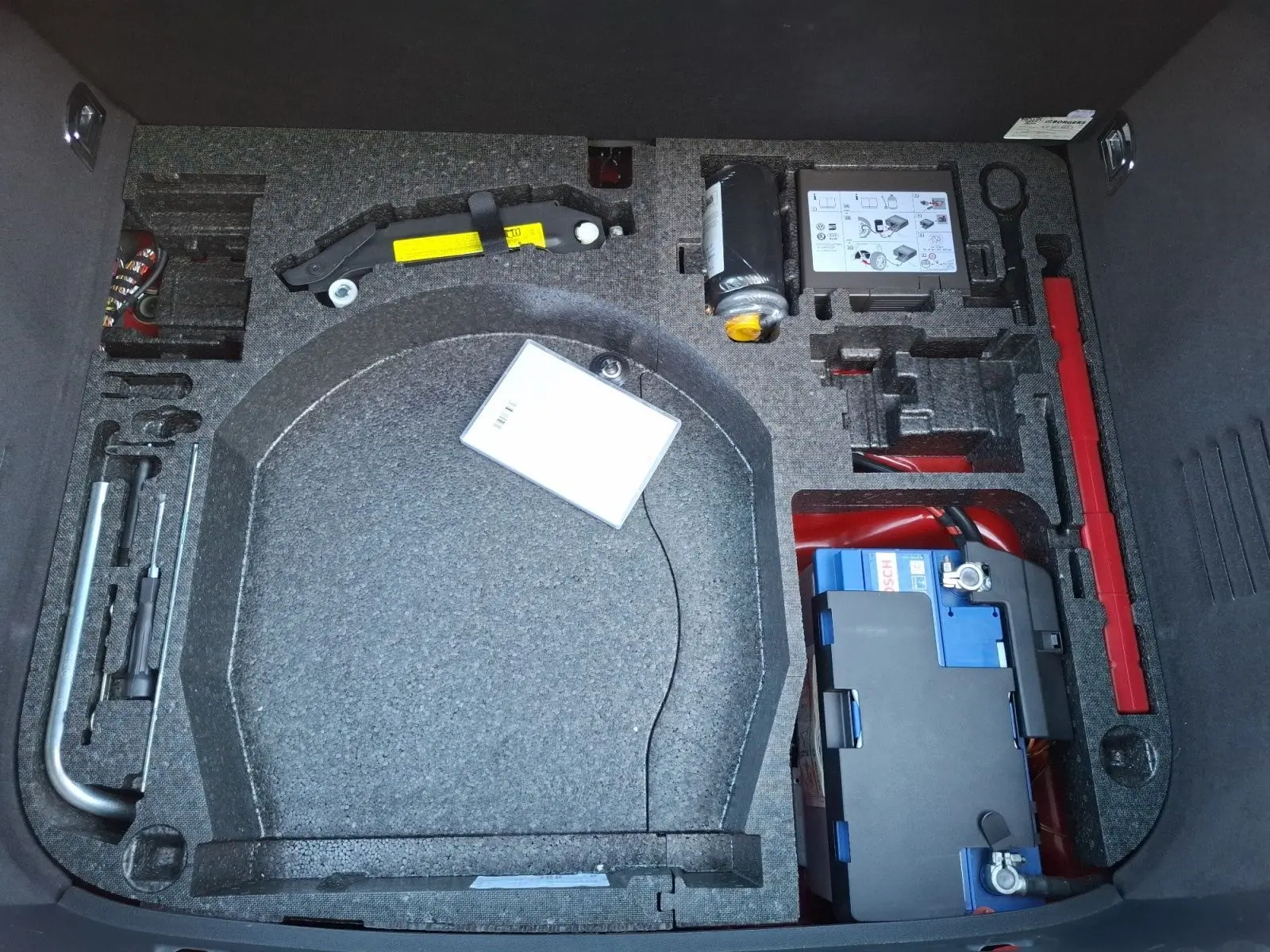 Coffre ouvert d’un Audi TT 3.2 V6 Quattro rouge de 2007, montrant le rangement pour roue de secours et outils intégrés.