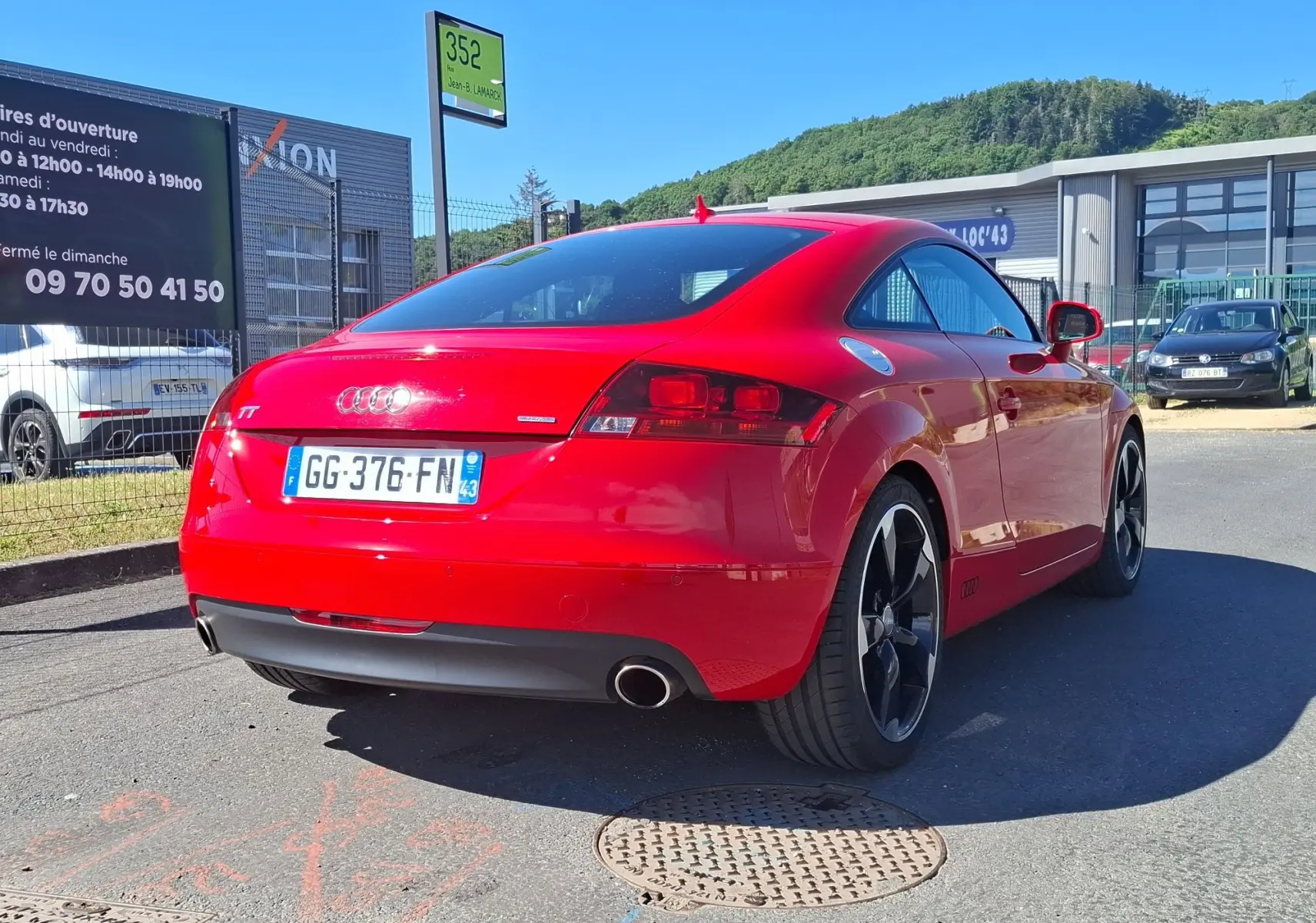 Audi TT 3.2 V6 Quattro rouge vue 3/4 arrière droit, avec jantes alliage noires et double sortie d'échappement.