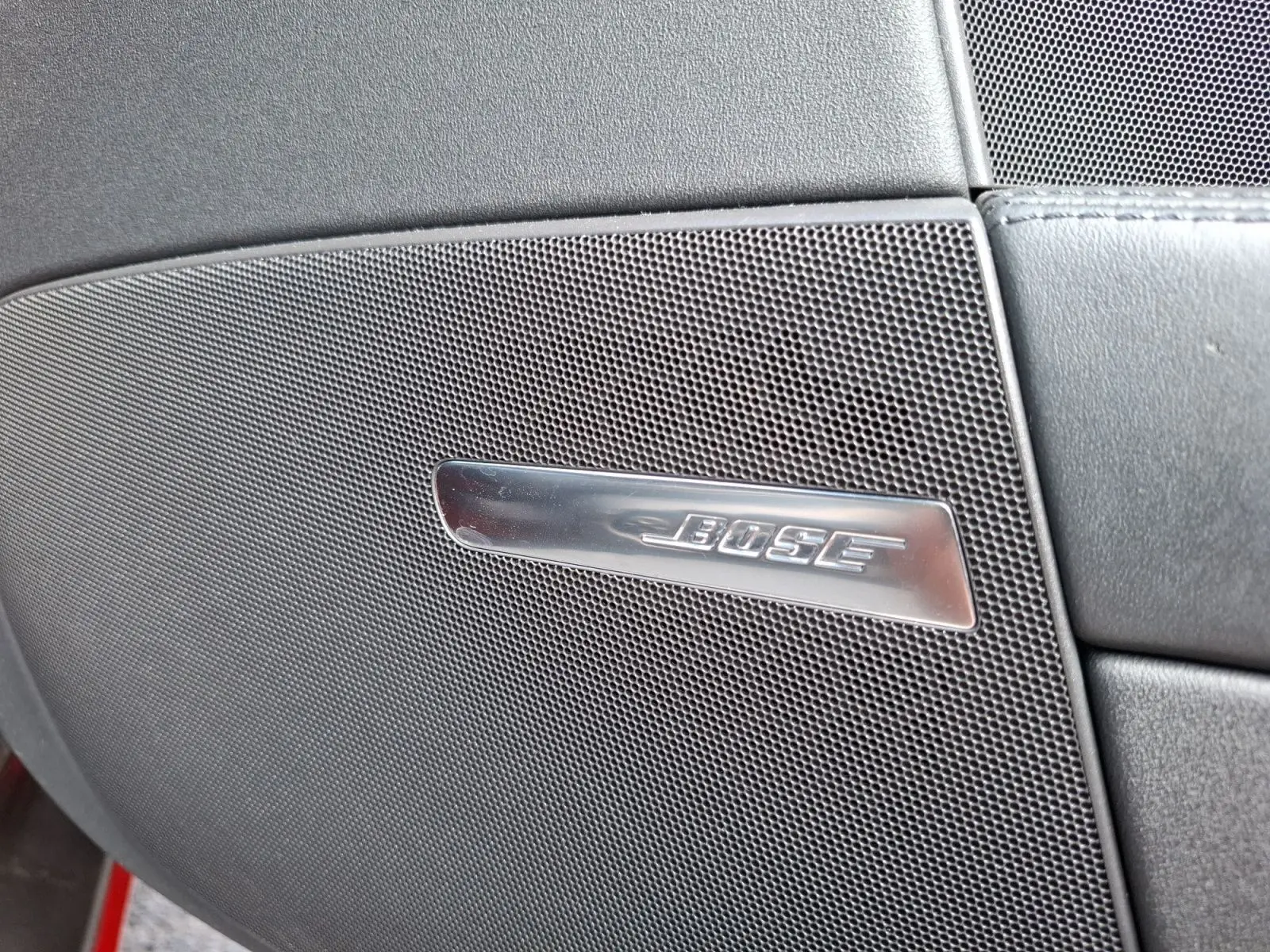 Gros plan sur le haut-parleur Bose intégré dans la porte intérieure d'une Audi TT rouge, version 3.2 V6 Quattro.