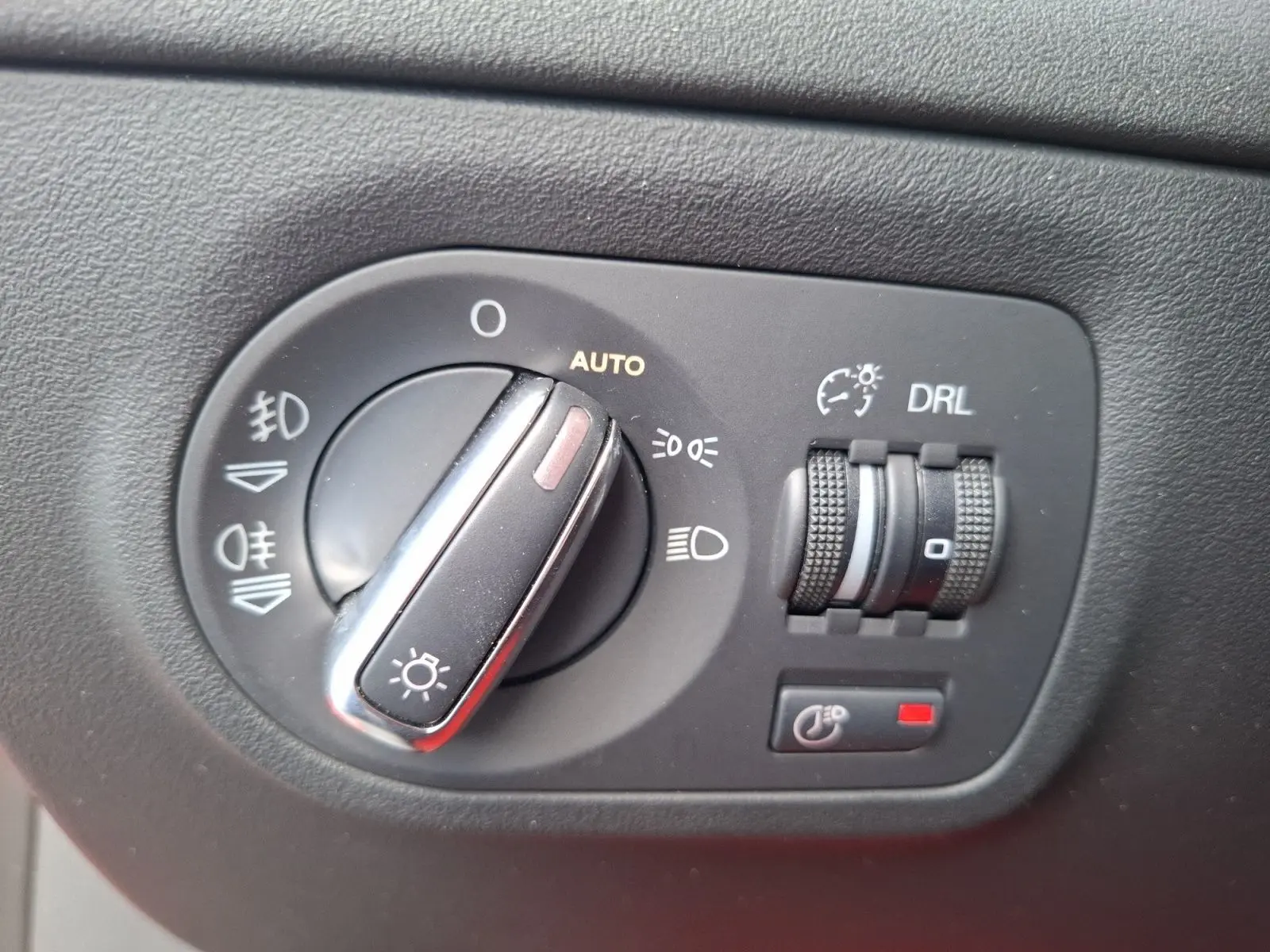 Gros plan sur le bouton de commande des phares et réglages lumineux de l’Audi TT 3.2 V6 Quattro rouge de 2007.