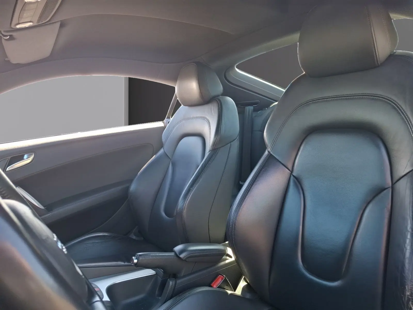 Vue intérieure des sièges avant en cuir noir de l'Audi TT 3.2 V6 Quattro de 2007, côté conducteur et passager.