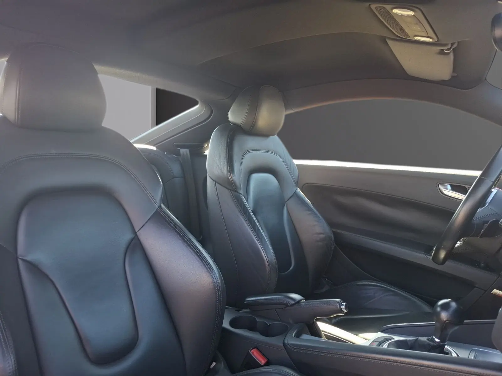 Vue intérieure côté droit de l’Audi TT 3.2 V6 Quattro 2007 avec sellerie cuir noire et volant partiellement visible.