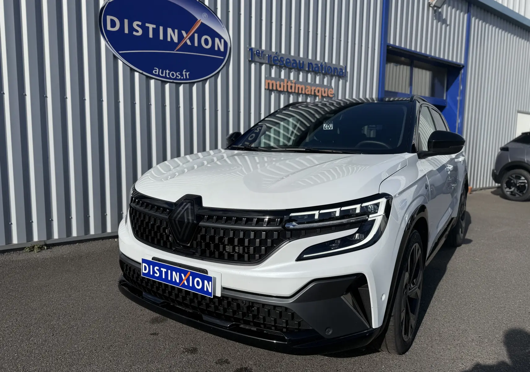 Renault Austral Hybrid blanc nacré avec toit noir, vue 3/4 avant droit, calandre noire et phares LED distinctifs.