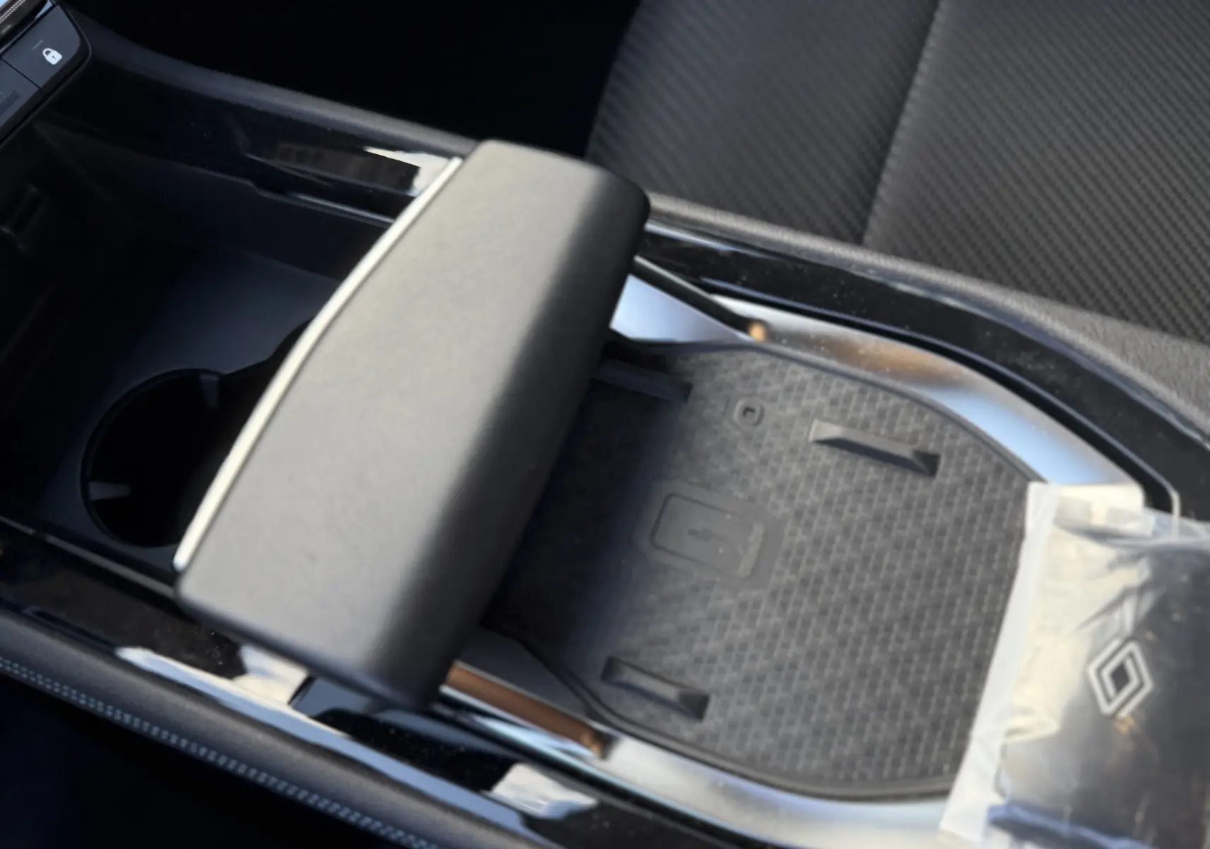 Gros plan sur la console centrale noire du Renault Austral Hybrid 2025, avec accoudoir et espace de rangement.