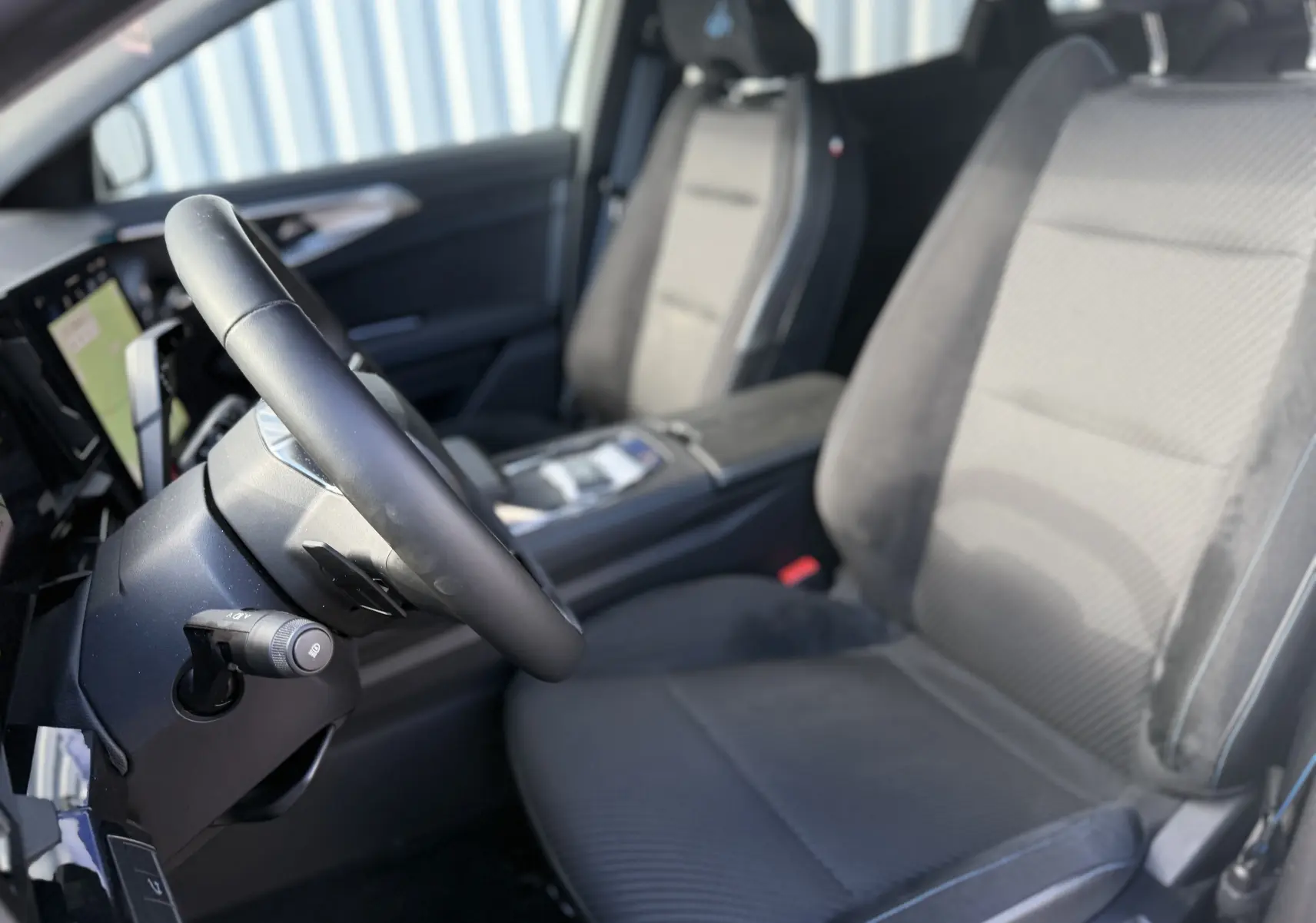 Vue intérieure côté conducteur du Renault Austral Hybrid 2025, sièges en tissu et cuir noir avec volant multifonction.