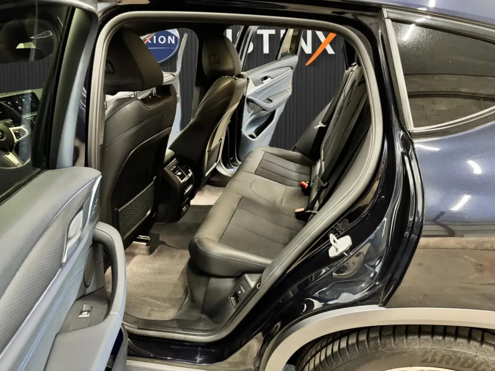 Vue côté droit arrière ouverte du BMW X4 XDrive 20d 2020 en Carbonschwarz, montrant l'intérieur gris noir et les sièges arrière.