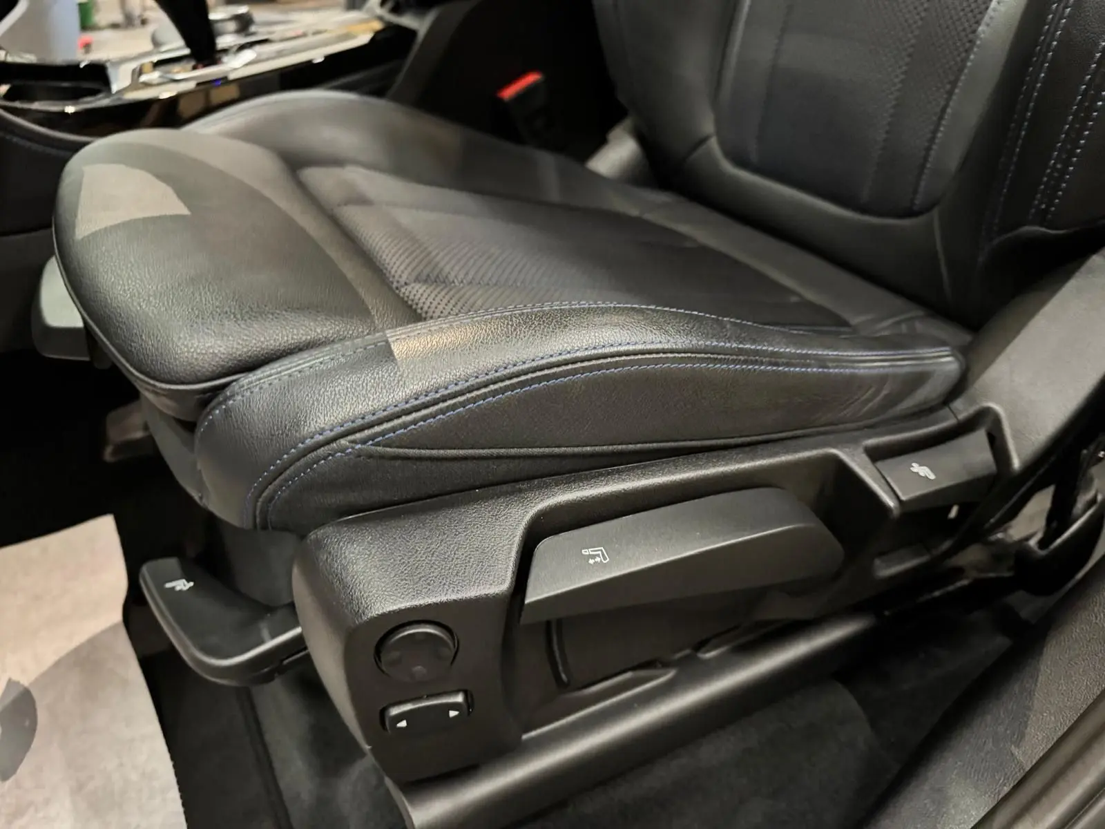 Gros plan sur le siège conducteur en cuir noir avec surpiqûres bleues du BMW X4 XDrive 20d 2020, côté gauche.