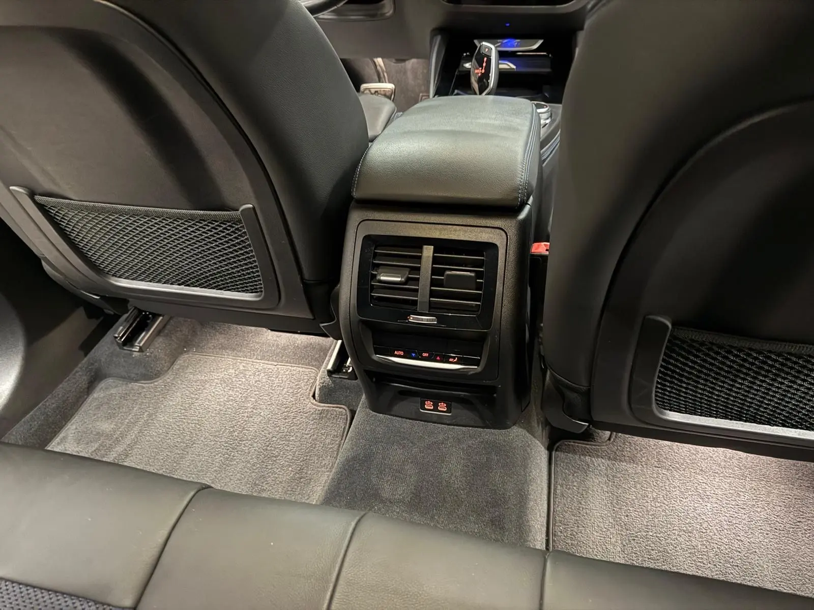 Vue arrière de l'habitacle noir d'une BMW X4 XDrive 20d 2020, montrant la console centrale avec aérateurs et commandes climatiques.