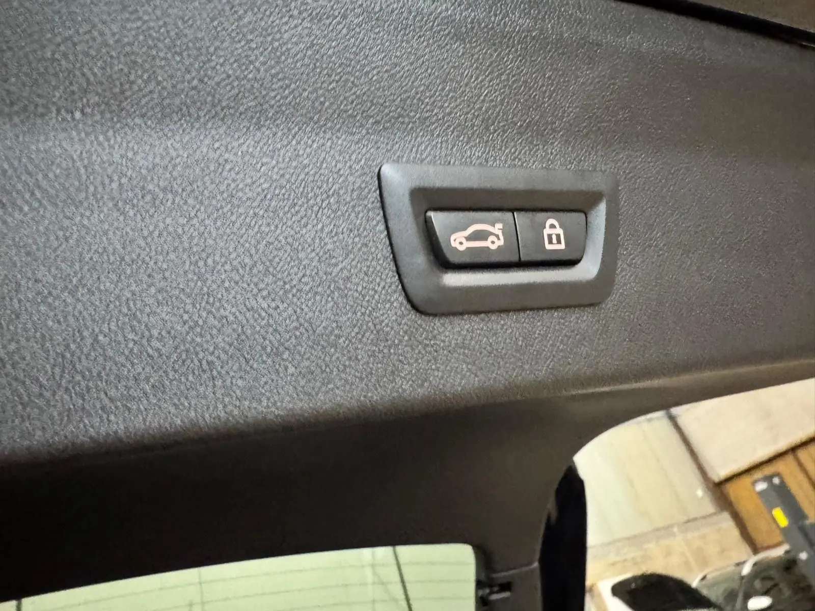 Gros plan sur le bouton d'ouverture et verrouillage du coffre, intérieur noir du BMW X4 XDrive 20d 2020.