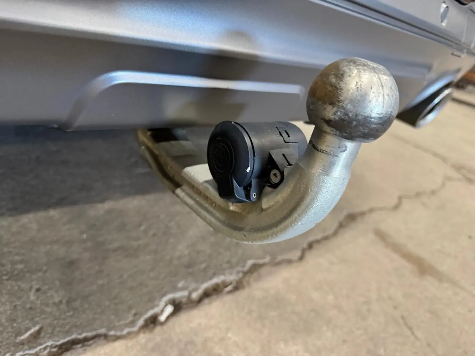 Gros plan sur l'attelage d'une BMW X4 Carbonschwarz 2020, mettant en valeur la boule d'attelage métallique et la prise électrique noire.