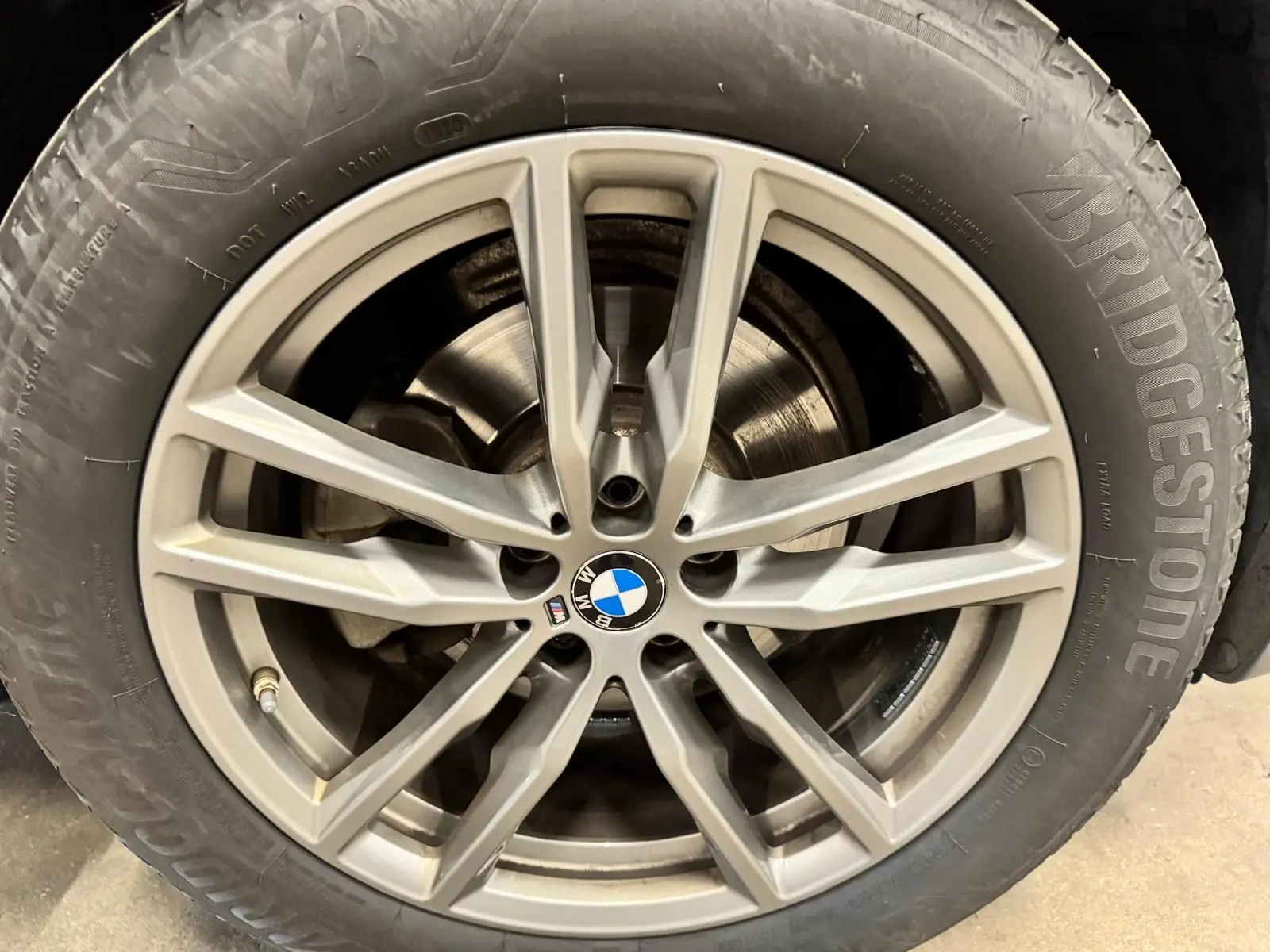 Gros plan sur la jante alliage argentée avec logo BMW au centre, montée sur pneu Bridgestone.
