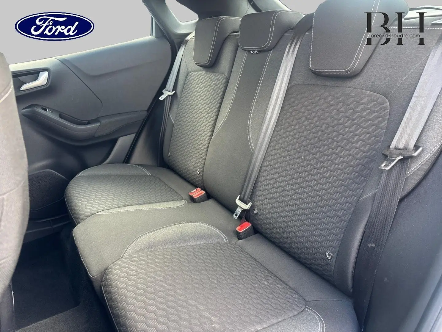Vue intérieure côté arrière droit du Ford Puma 2023, montrant la banquette noire avec ceinture et appuie-têtes intégrés.
