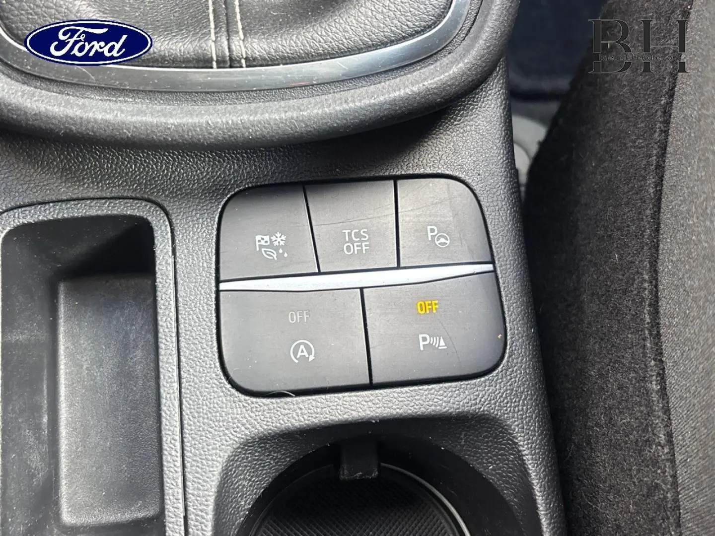 Gros plan sur les commandes de la console centrale du Ford Puma gris, avec boutons d’aide à la conduite et rangement.