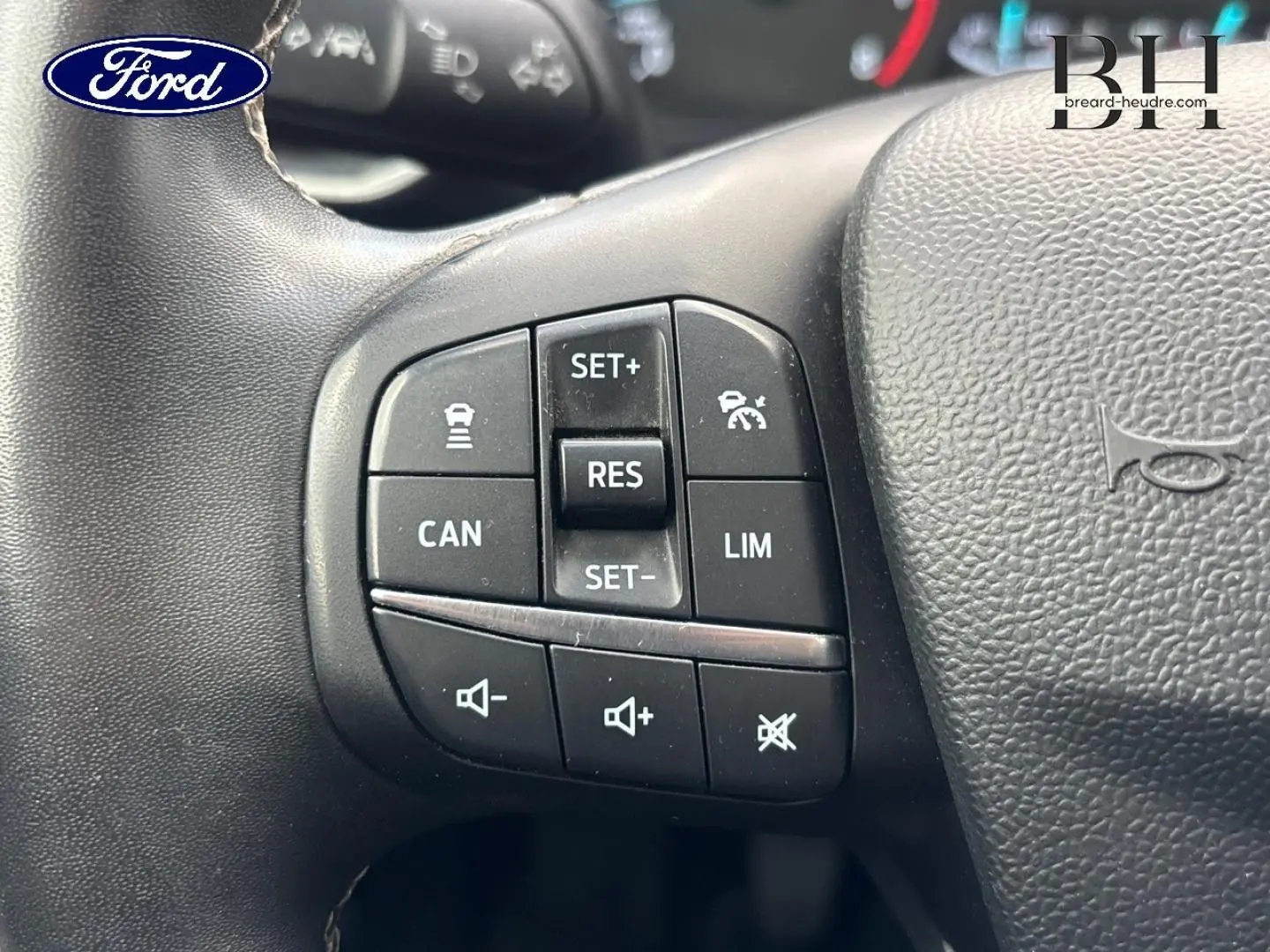 Gros plan sur les commandes multifonctions au volant noir du Ford Puma gris Solar Métallisée, version 2023 Titanium Business.