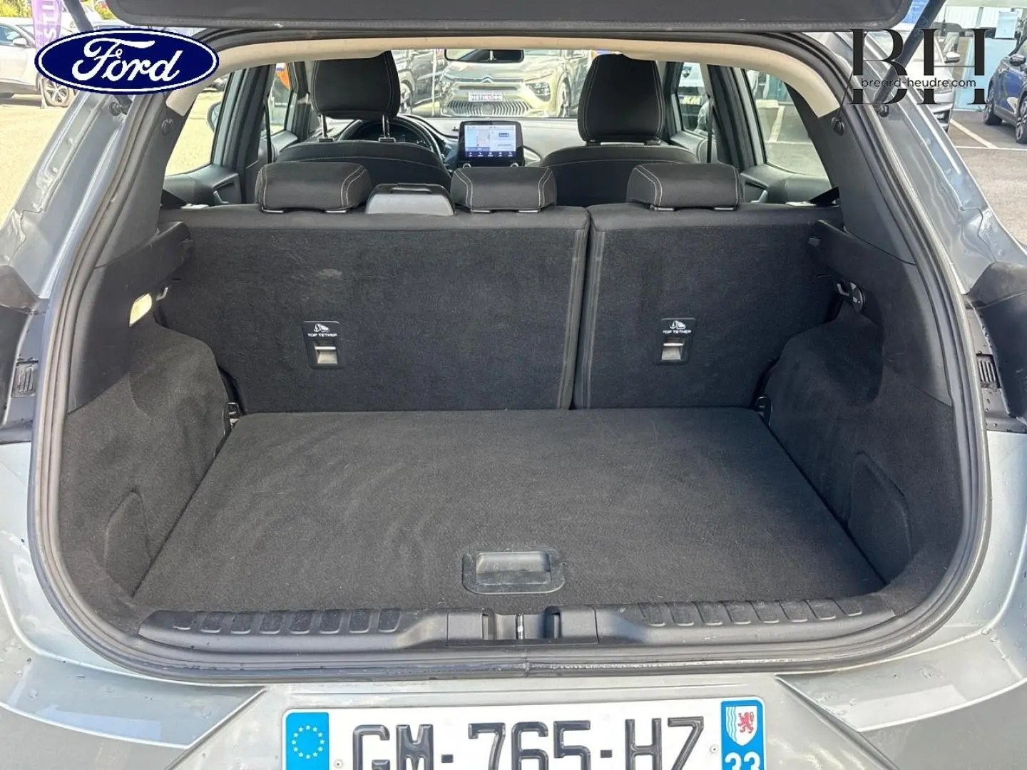 Coffre ouvert d’un Ford Puma gris Solar métallisé, vue arrière montrant l’espace de chargement et la banquette rabattue.