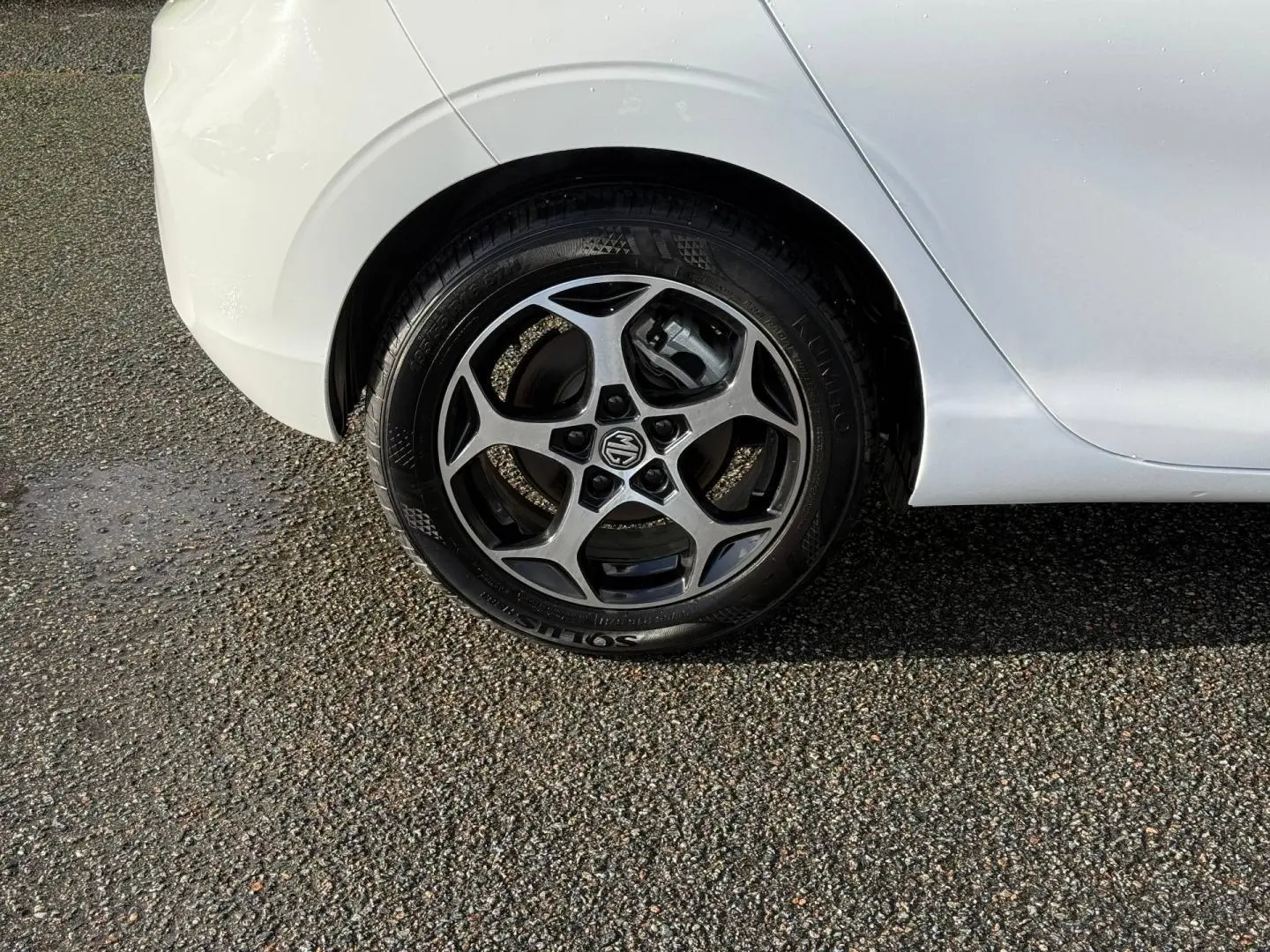 Gros plan sur la roue arrière droite d'une MG3 blanche avec jante alu à cinq branches distinctives.