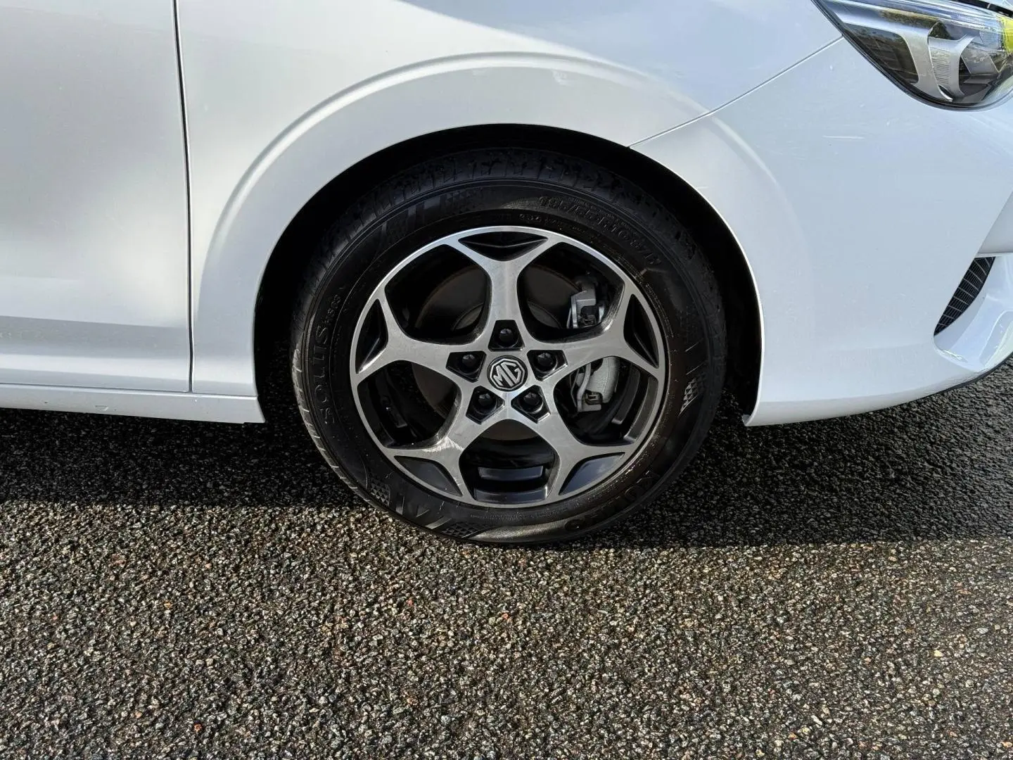 Gros plan sur la roue avant droite et une partie de la carrosserie blanche du MG3 1.5 Hybrid+ 195ch Luxury.