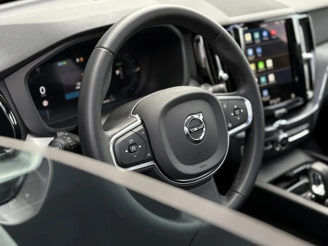 Volant simili-cuir noir avec logo Volvo, tableau de bord digital et écran tactile dans l'habitacle du XC60 2024.