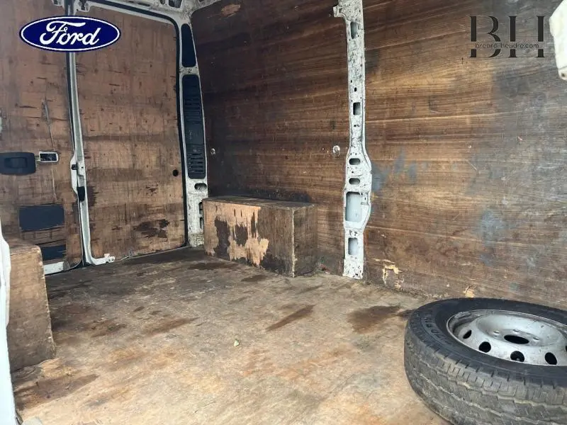 Vue intérieure arrière du Citroën Jumper blanc banquise, montrant l'espace de chargement en bois usé avec une roue de secours.
