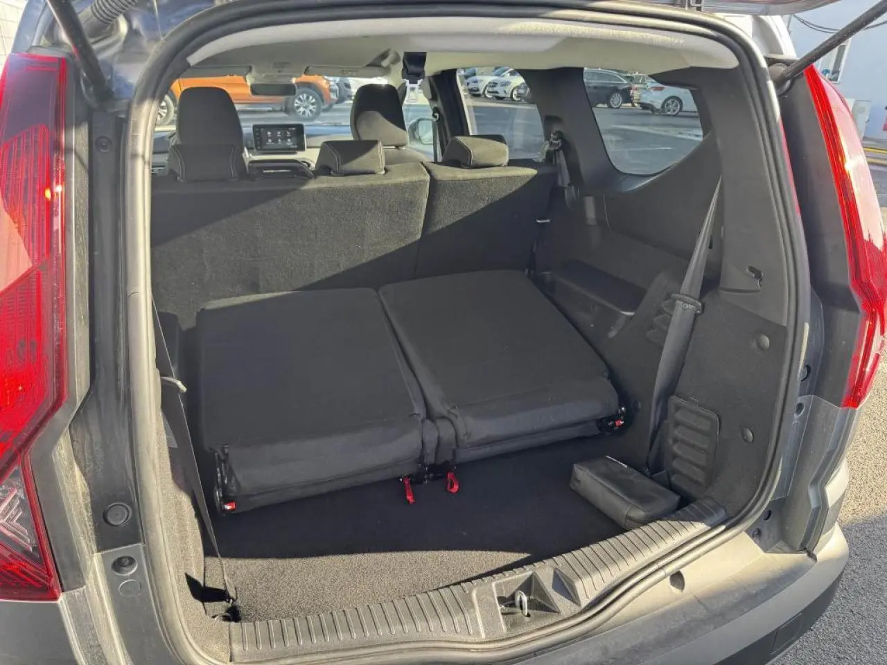 Vue arrière du coffre du Dacia Jogger gris schiste, sièges rabattus pour agrandir l'espace de chargement.