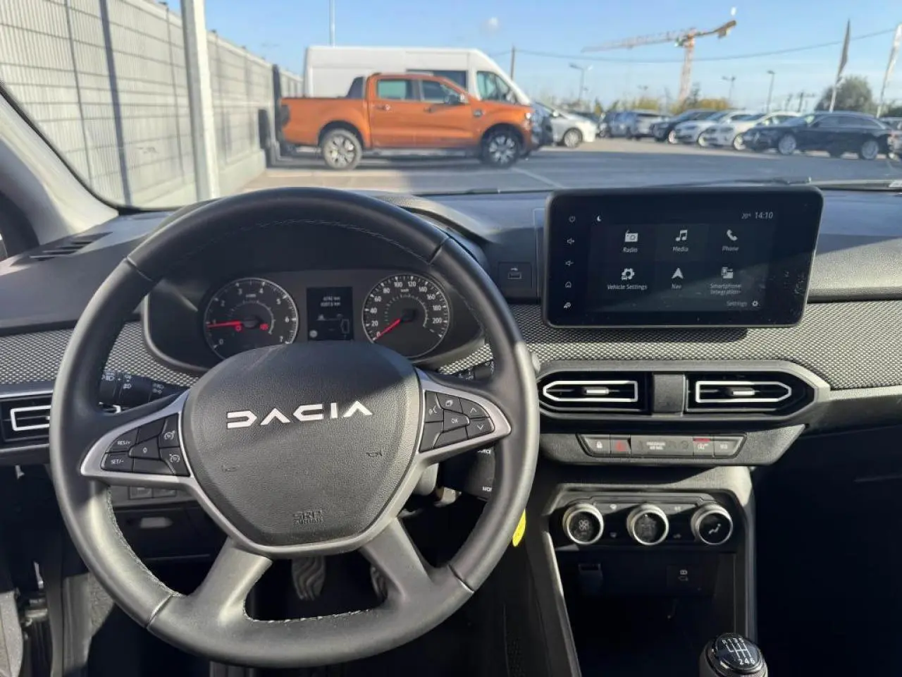 Vue intérieure centrée sur le volant DACIA et l’écran tactile 8 pouces du tableau de bord, ambiance noire.