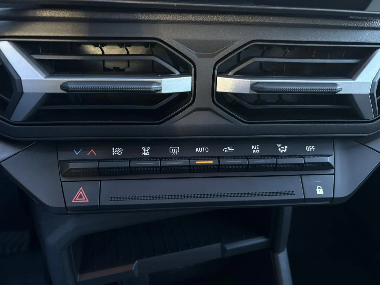 Détail de la console centrale noire du Dacia Duster 2025, avec commandes climatisation et aérateurs hexagonaux.