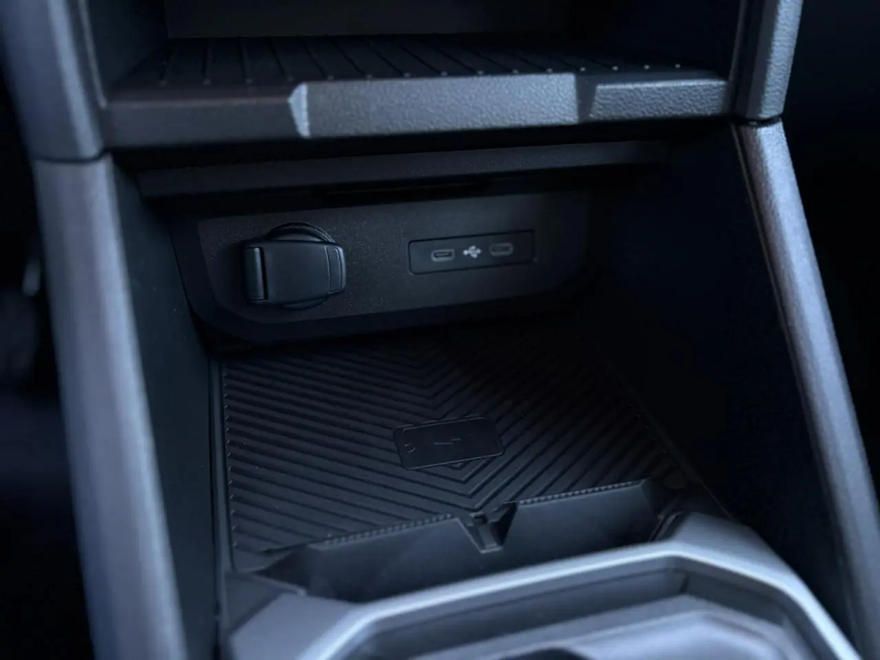Gros plan sur la console centrale noire du Dacia Duster 2025, montrant les ports USB et un espace de rangement.