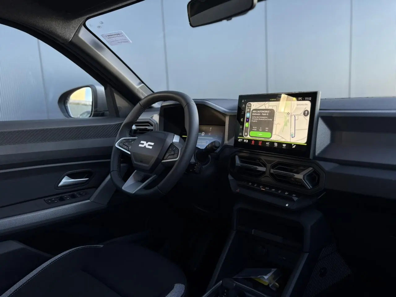 Vue intérieure côté conducteur du Dacia Duster 2025 noir nacré, avec tableau de bord digital et écran tactile central.