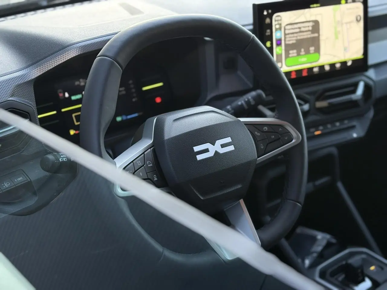 Vue rapprochée du volant noir du Dacia Duster 2025 avec tableau de bord digital et écran tactile central allumé.