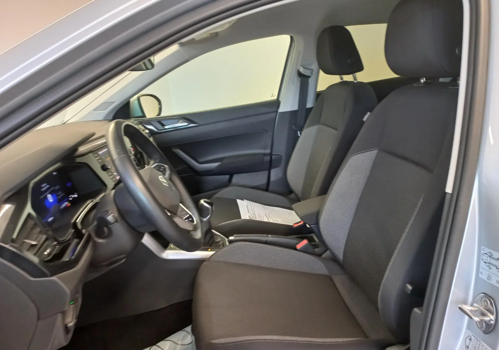 Vue intérieure côté conducteur du Volkswagen Taigo 2025 avec sièges noirs et volant multifonction.