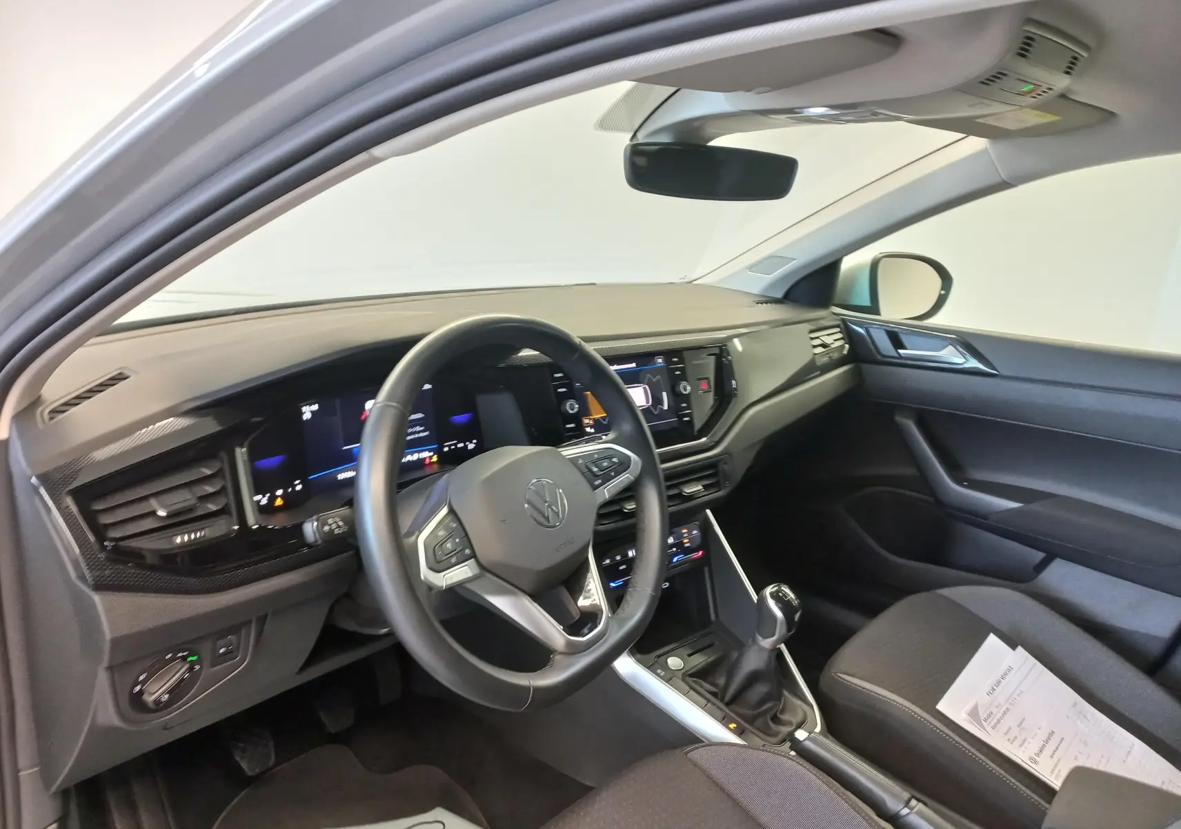 Vue intérieure côté conducteur du Volkswagen Taigo 2025, tableau de bord moderne avec volant multifonction et boîte manuelle.