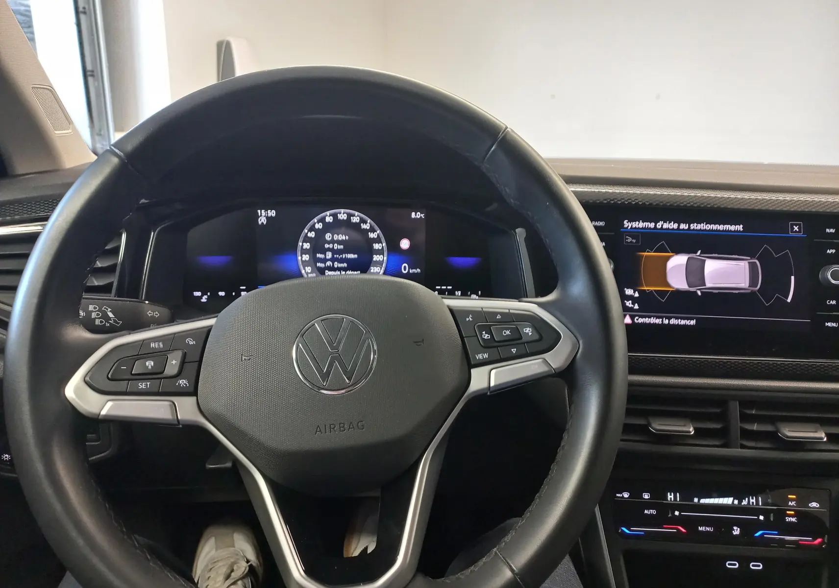 Vue intérieure centrée sur le volant multifonction du Volkswagen Taigo 2025 avec affichage numérique et aide au stationnement.