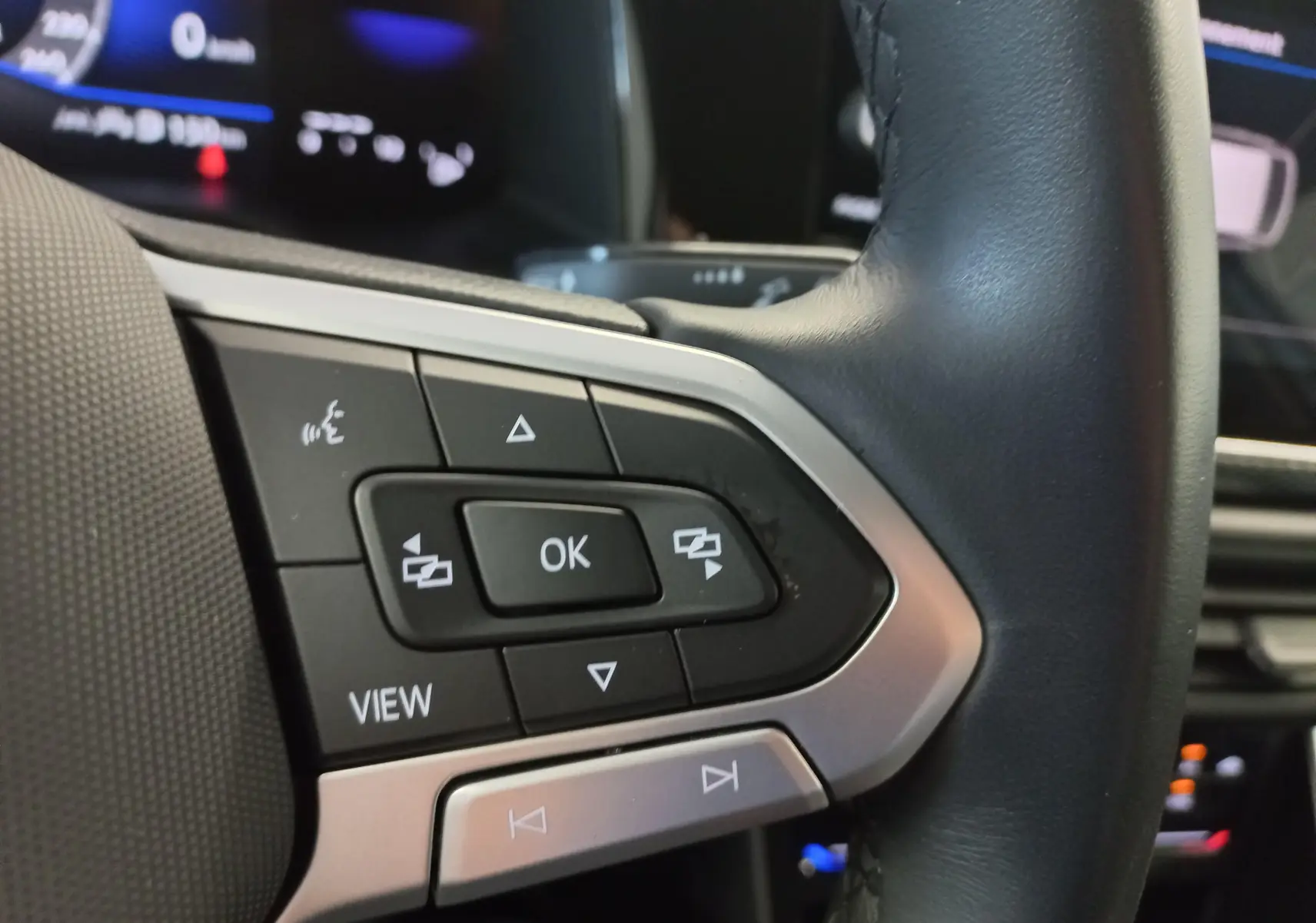 Gros plan sur les commandes au volant côté gauche du Volkswagen Taigo 2025, finition Reflet d'argent, avec boutons multifonctions.