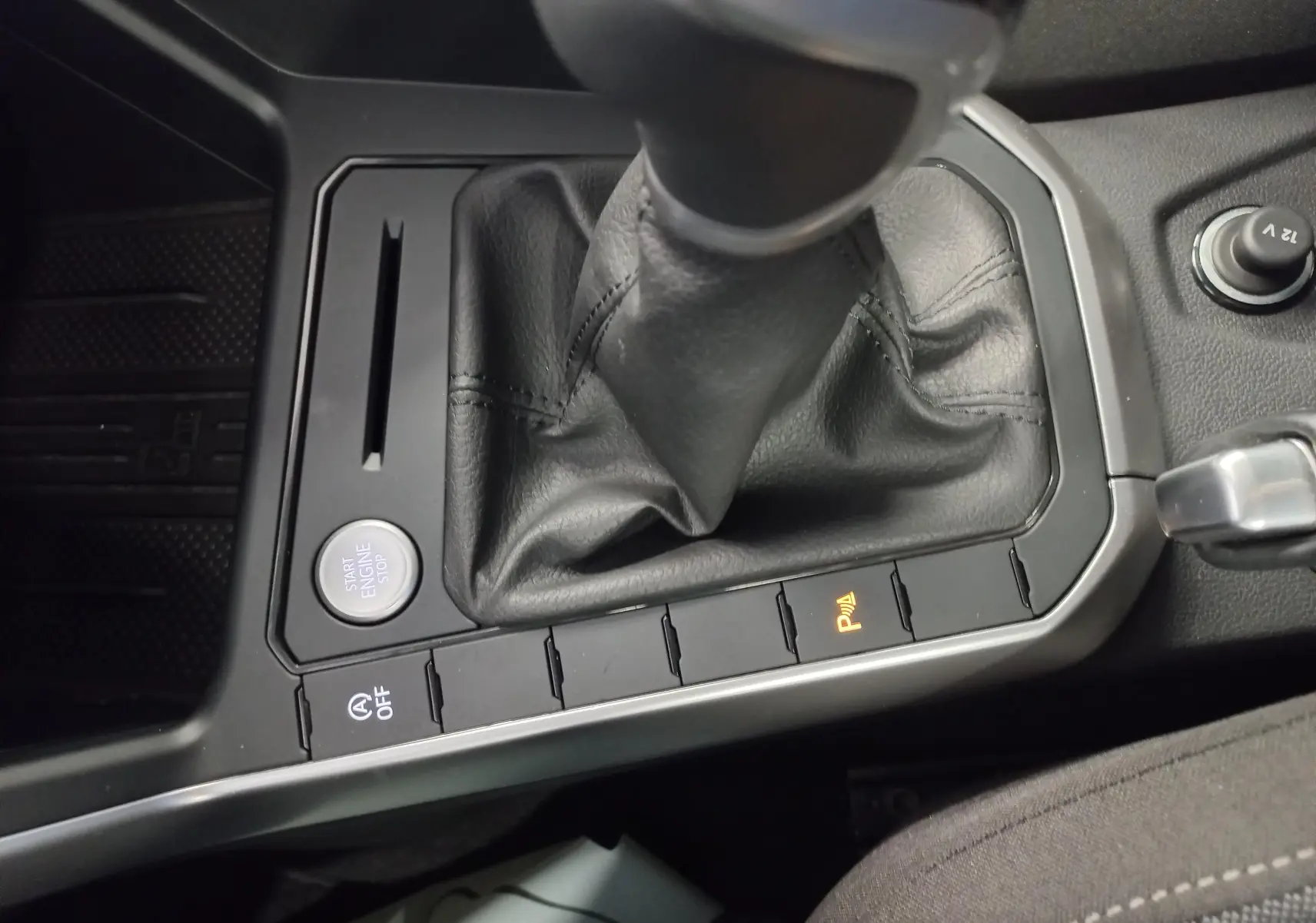 Gros plan sur la console centrale du Volkswagen Taigo 2025, avec levier de vitesse manuel et bouton Start/Stop.