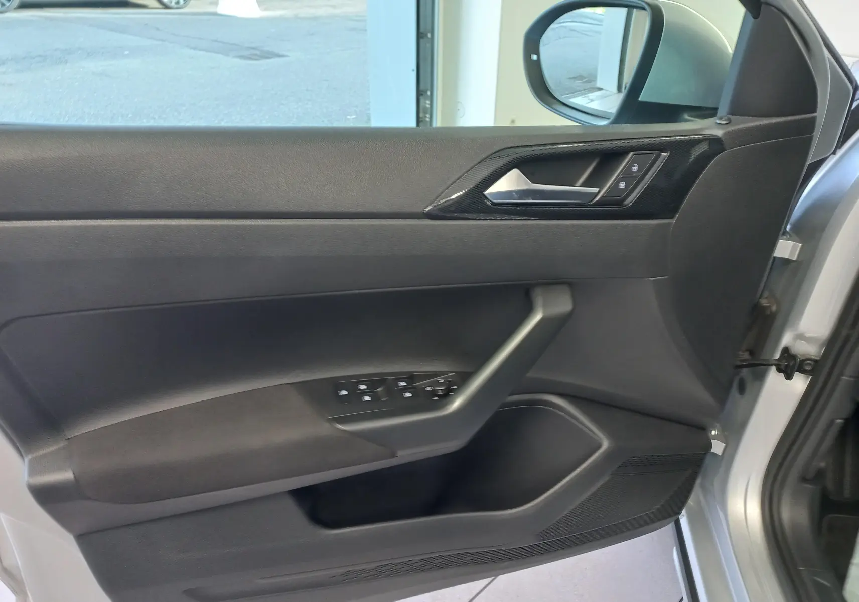 Vue intérieure de la porte avant droite du Volkswagen Taigo 2025 en Reflet d'argent, avec commandes de vitres et serrure.