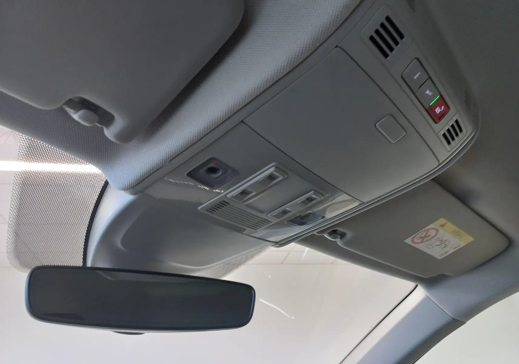 Vue intérieure du plafond avant avec rétroviseur et commandes d'éclairage dans un Volkswagen Taigo argent métallisé.