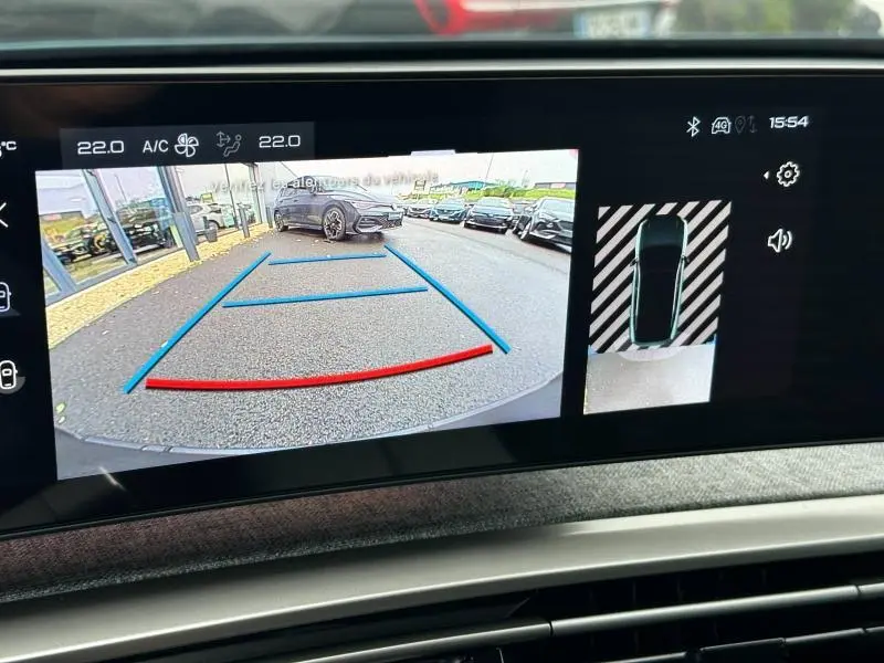 Écran de caméra de recul montrant une Peugeot 3008 bleu en stationnement derrière, vue arrière avec lignes de guidage.