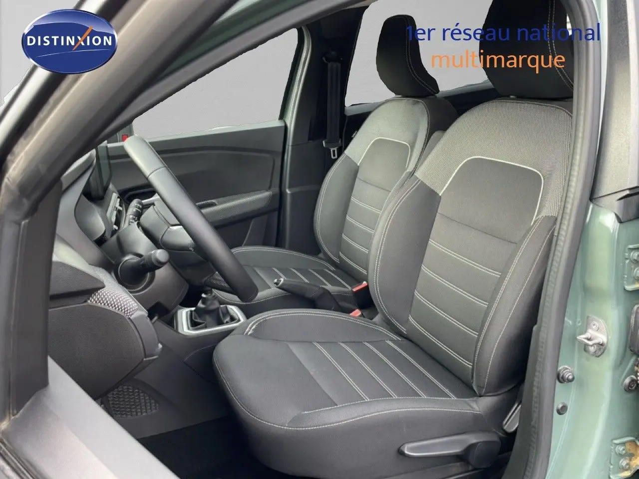 Vue intérieure côté conducteur du Dacia Jogger 2025 en kaki lichen, montrant les sièges avant en tissu noir et gris.