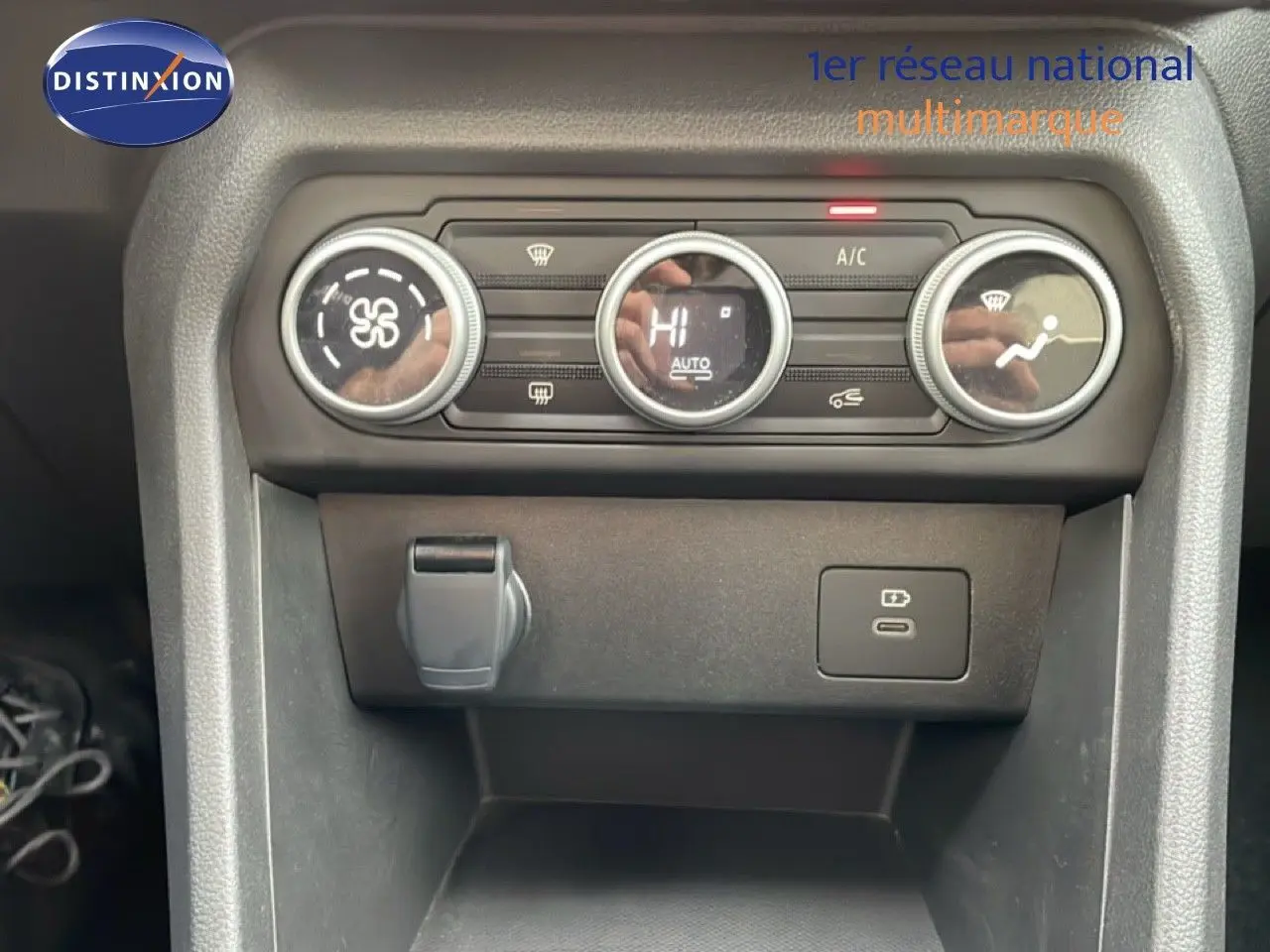 Gros plan sur la console centrale du Dacia Jogger kaki, montrant les commandes de climatisation et prises USB.