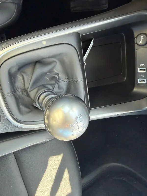 Gros plan sur le levier de vitesses manuel noir dans l'habitacle du Jeep Avenger blanc, avec ports USB et prise 12V visibles.