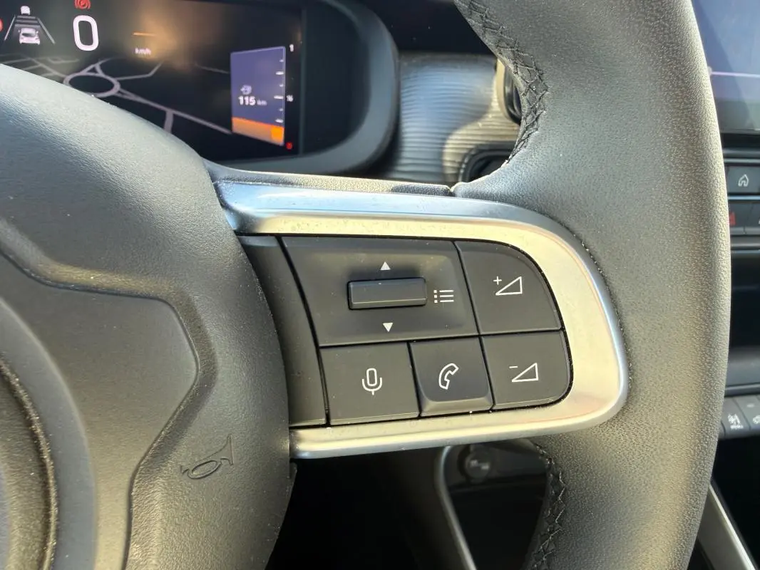 Gros plan sur les commandes au volant à droite du Jeep Avenger 2025, avec tableau de bord numérique en arrière-plan.