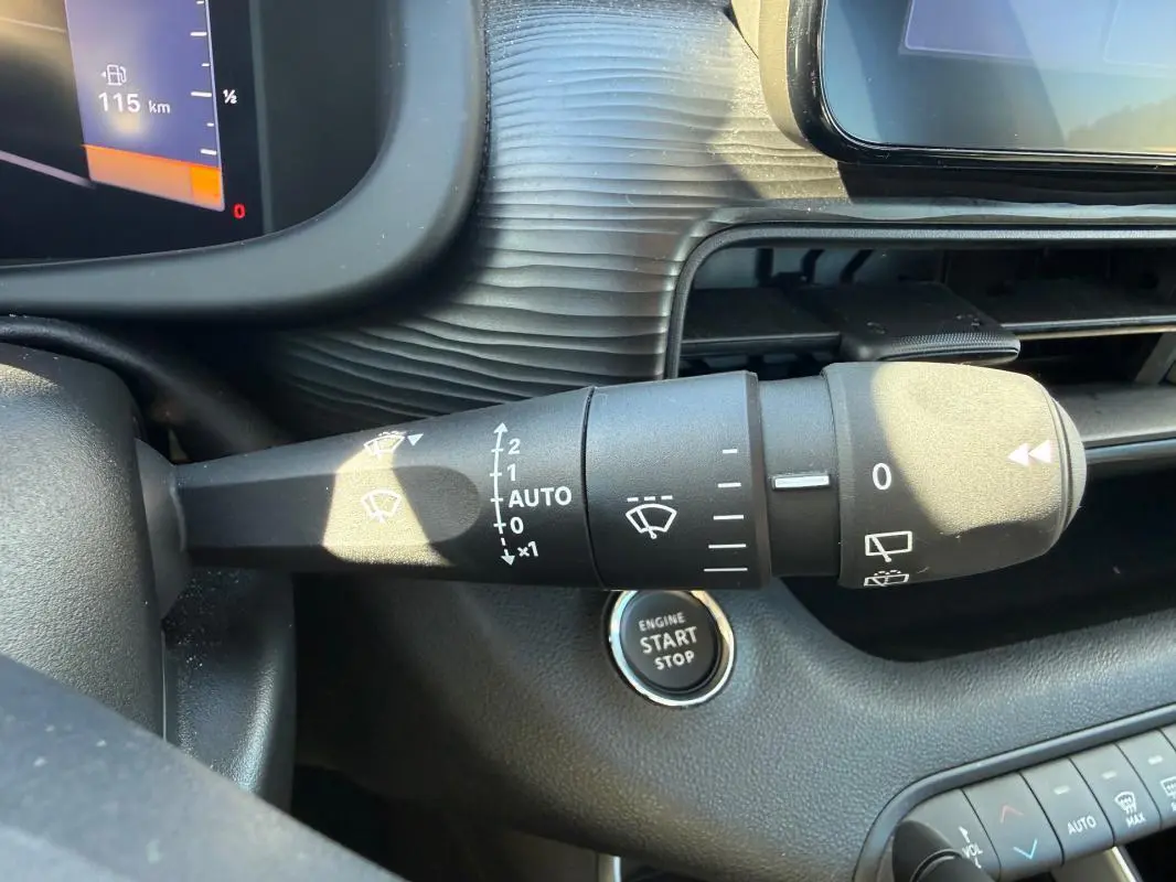 Gros plan sur la commande d'essuie-glace et le bouton start/stop du tableau de bord intérieur du Jeep Avenger blanc.